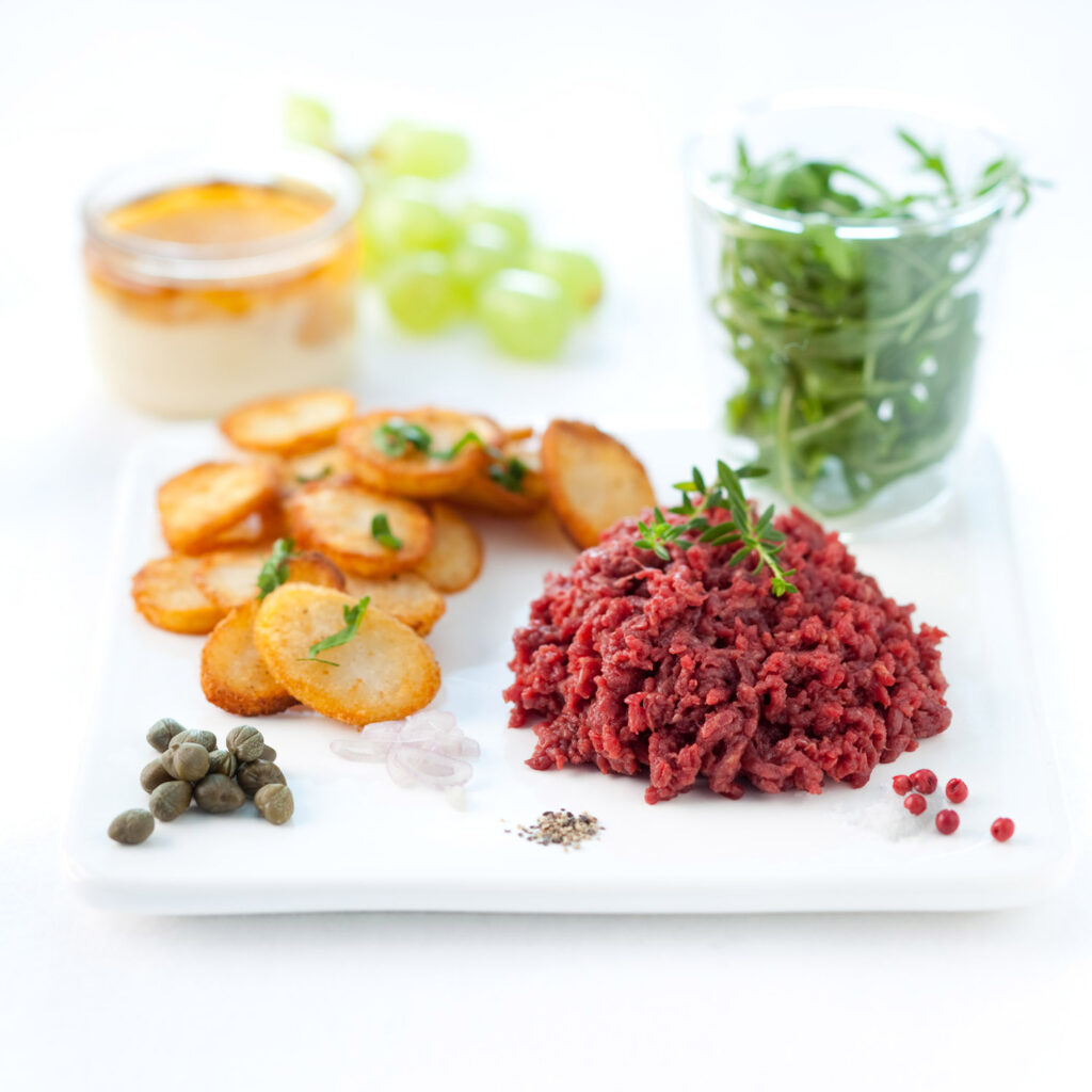 packshot produit sur fond blanc, d un tartare et pomme de terre saute et de la salade